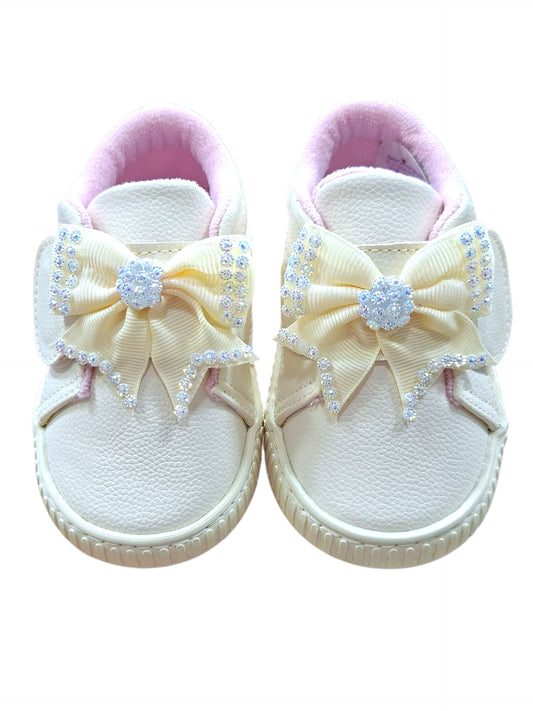 Tenis casuales Calzakids Moritas para niña en color blanco con moño decorativo brillante y detalles en rosa suave.